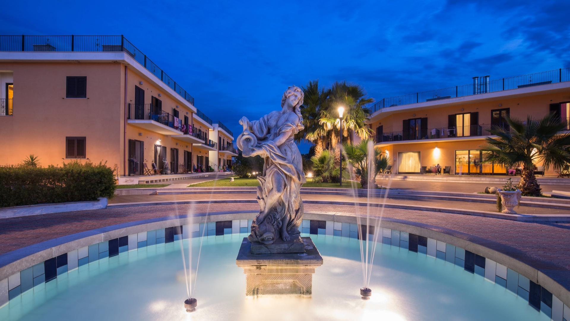 Statua in una fontana al centro di un complesso residenziale di sera.