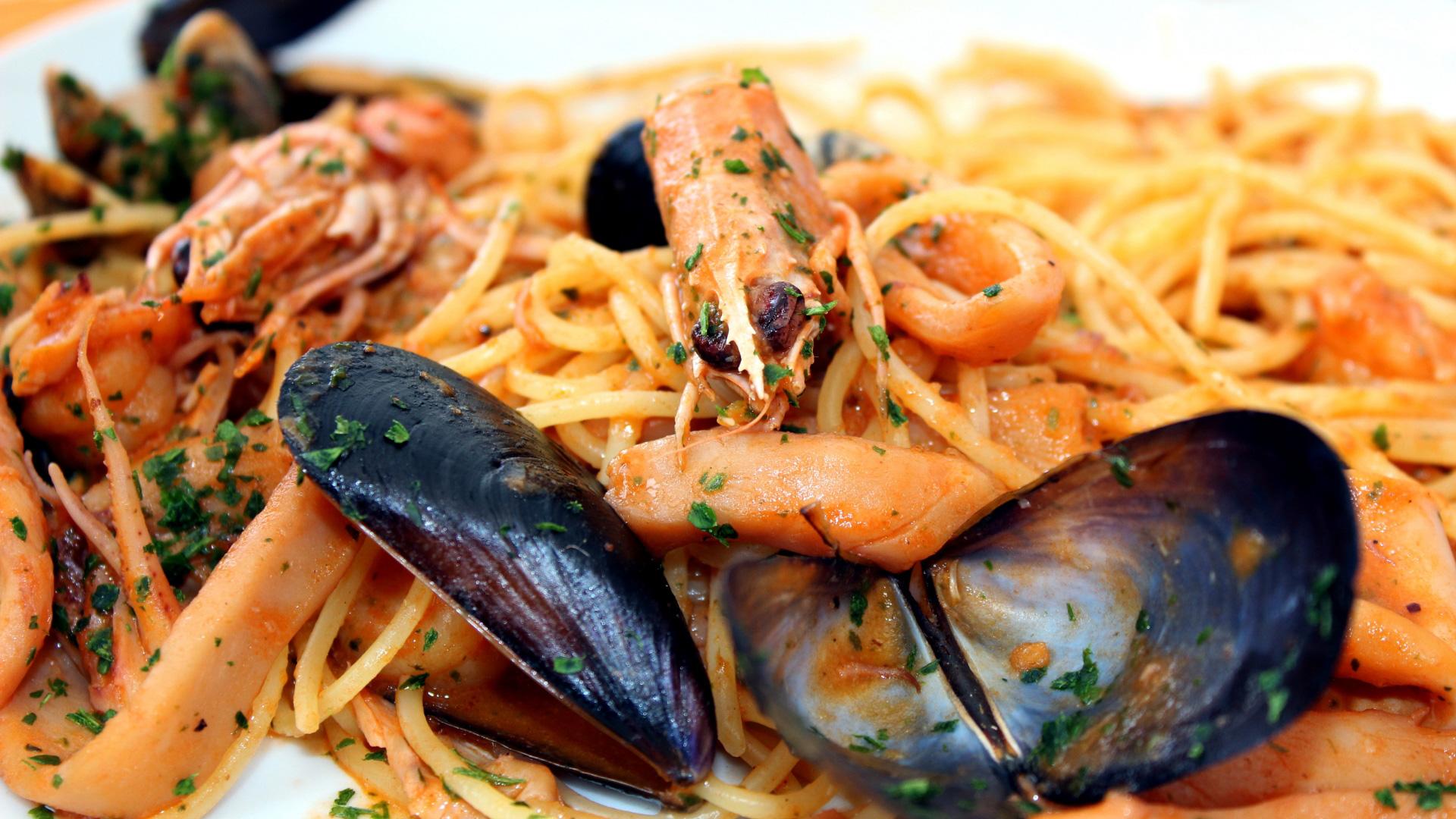 Spaghetti ai frutti di mare con gamberi, cozze e prezzemolo tritato.