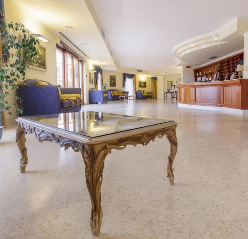 Elegante hall d'albergo con arredi classici, reception in legno e confortevoli aree salotto.